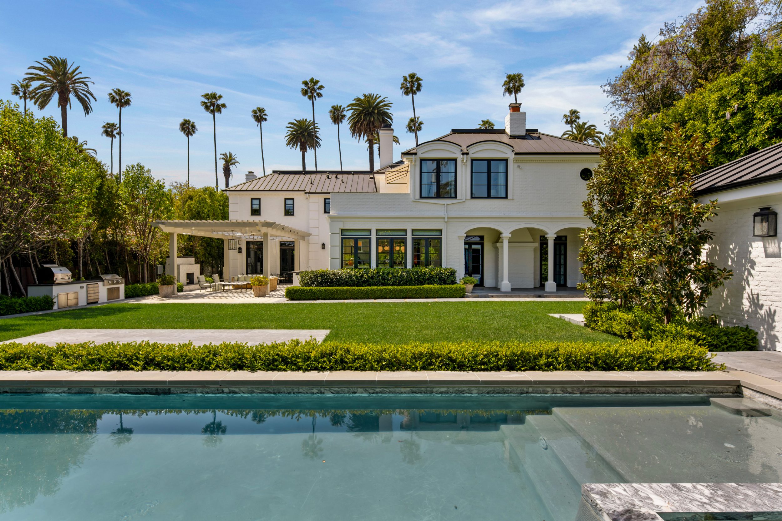 Rear garden, loggia, and pool beneath the palms